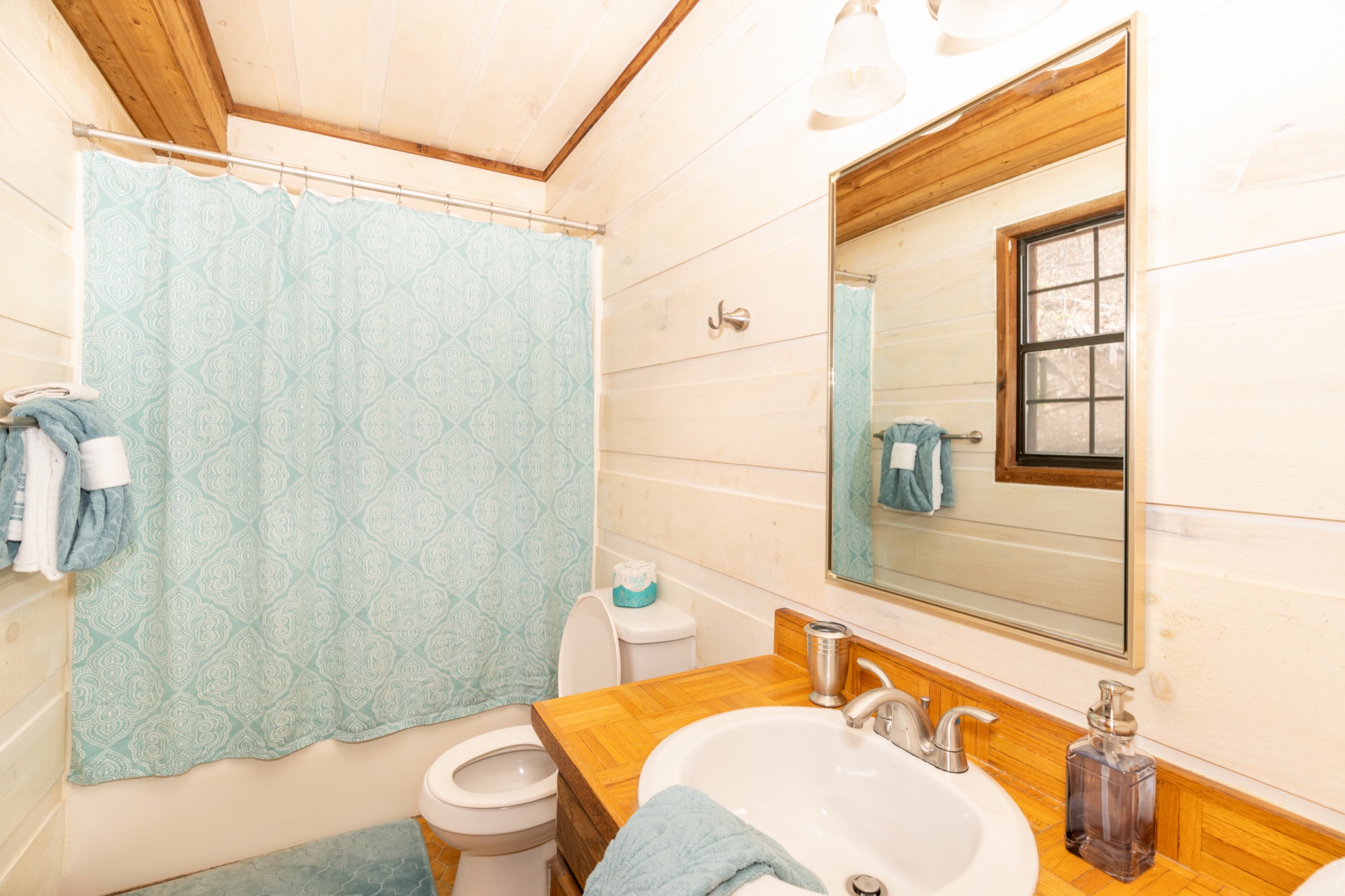 Rustic Retreat bathroom with a seafoam shower curtain and a wood framed vanity mirror